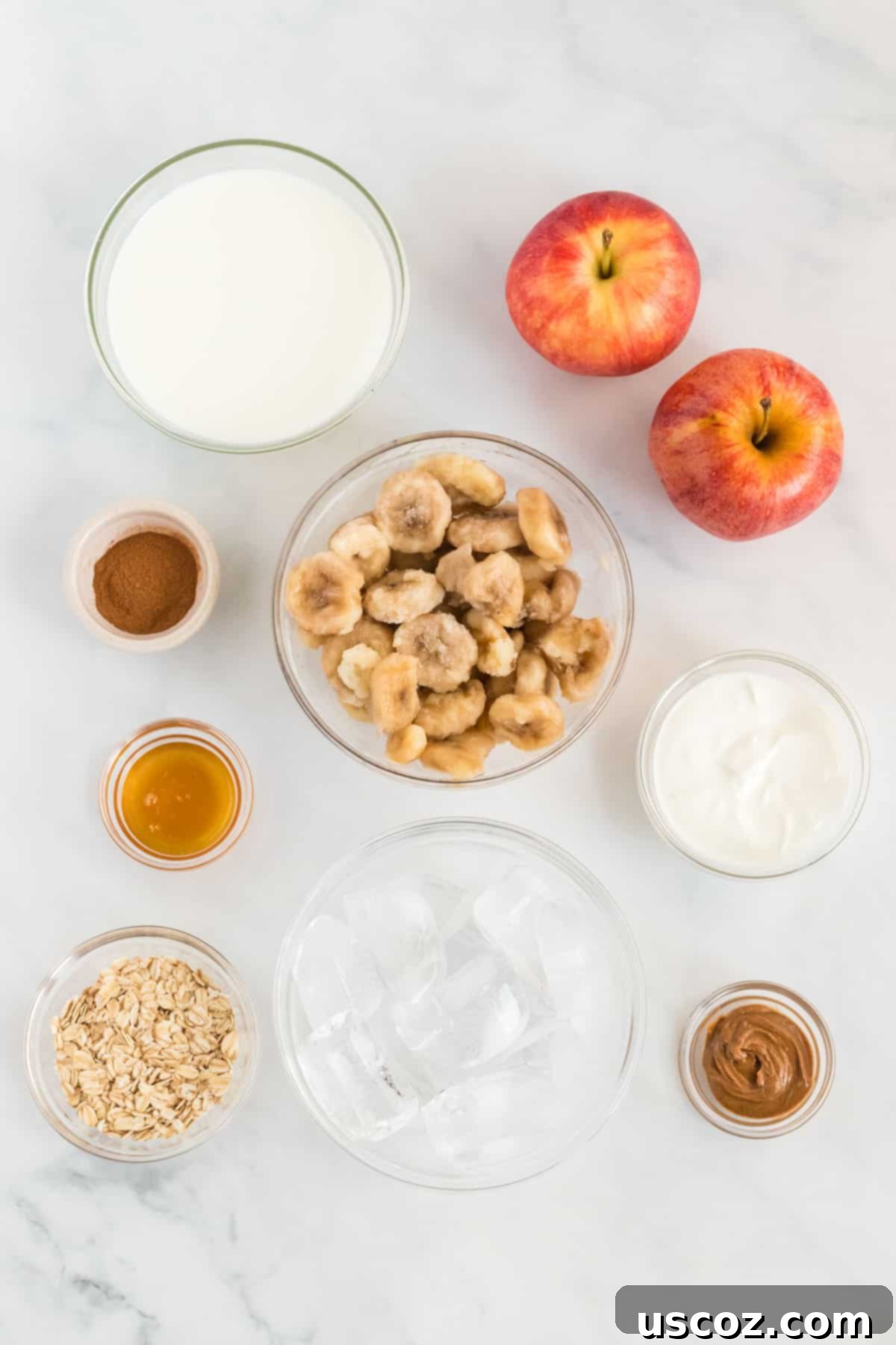 Liquid Apple Pie 3 All ingredients laid out on a table for an apple pie smoothie: apples, frozen bananas, Greek yogurt, cinnamon, honey, oats, almond butter, and milk