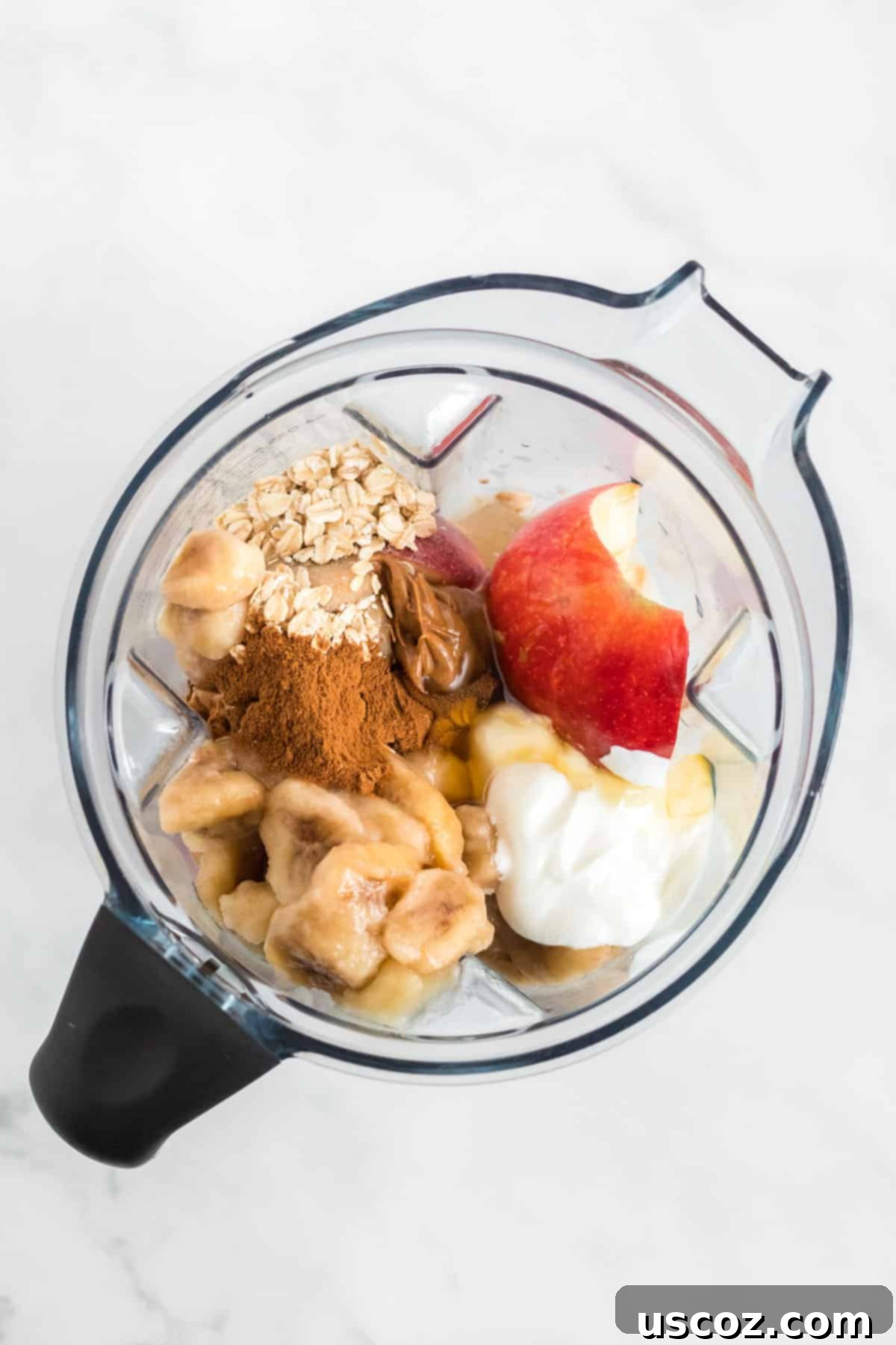 Liquid Apple Pie 5 All smoothie ingredients including apples, bananas, Greek yogurt, cinnamon, honey, oats, and almond butter loaded into a blender, ready to blend