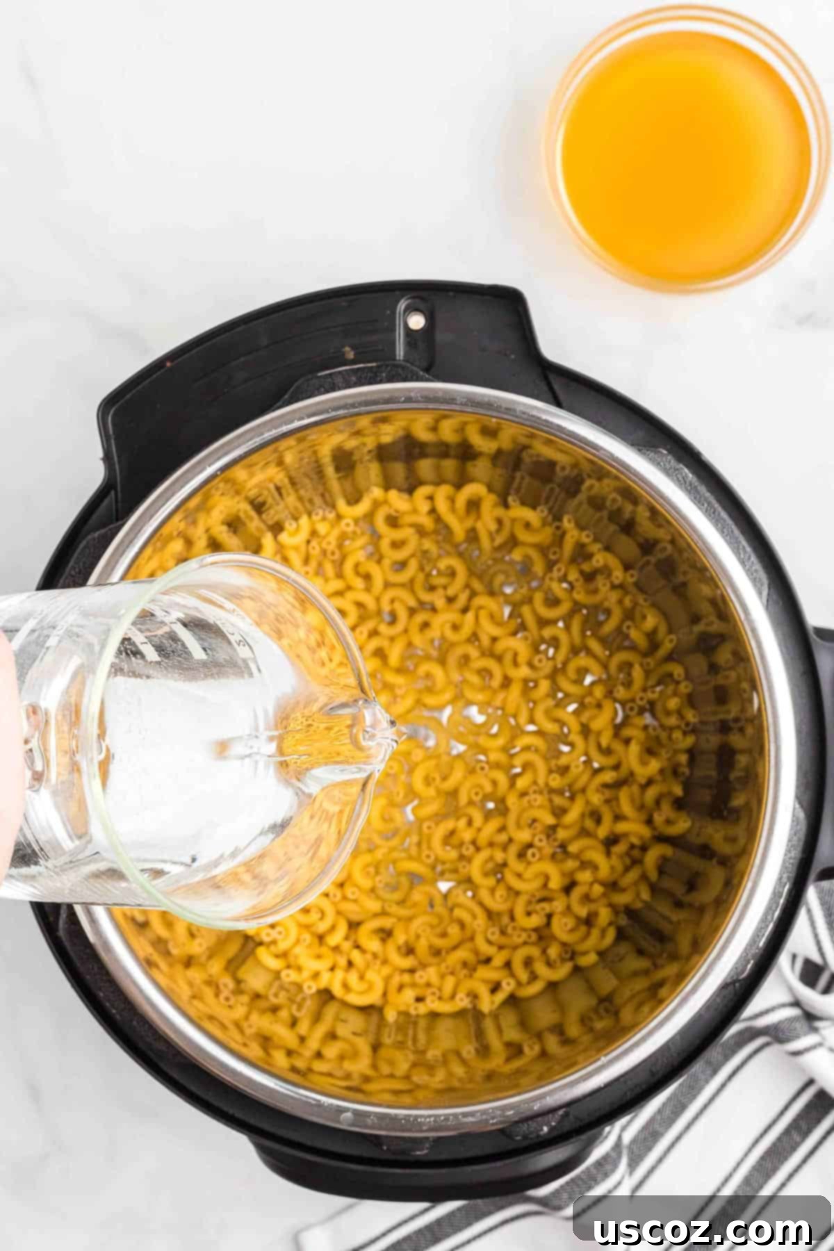 Creamy Instant Pot Mac and Cheese 5 pouring water over macaroni noodles in an instant pot