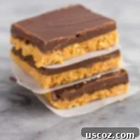 Delicious no bake chocolate peanut butter bars stacked neatly between pieces of wax paper, showcasing their perfect layers.