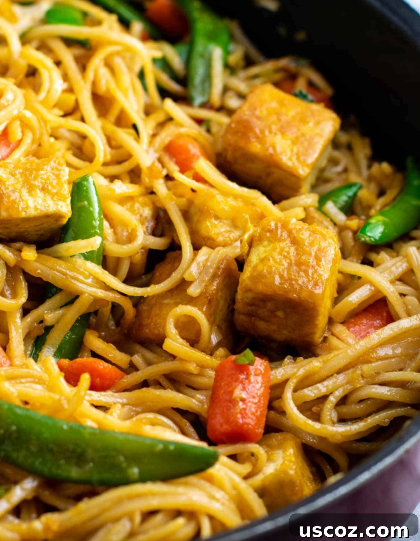 Vibrant Tofu Noodle Stir-Fry 7 Hand pouring homemade stir fry sauce into a skillet with vegetables and tofu.