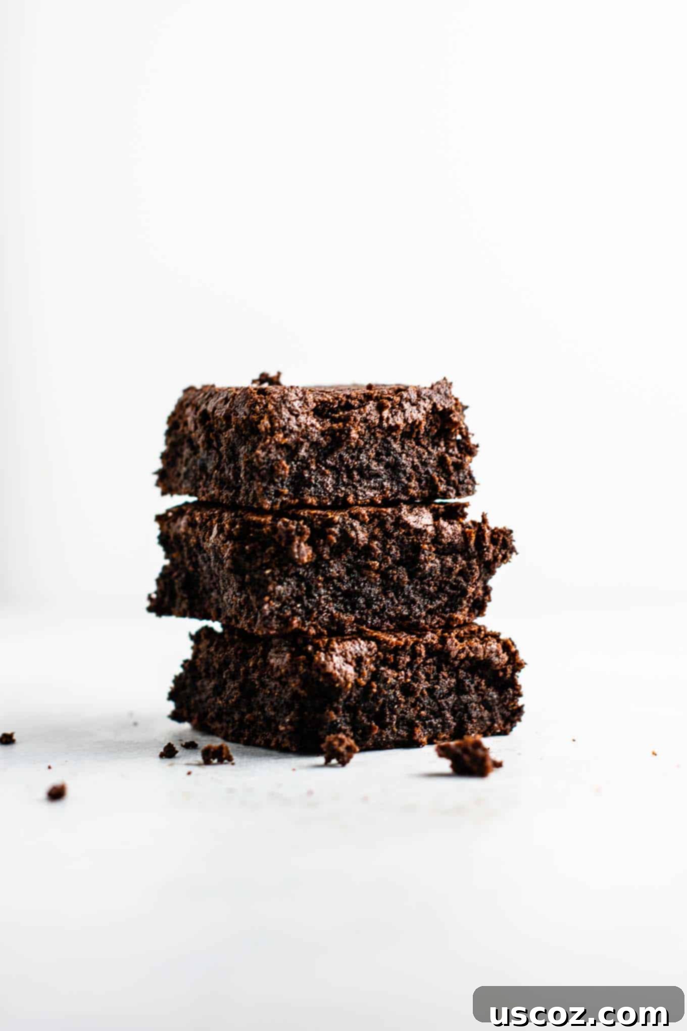 Gluten-free brownie batter poured into a parchment-lined 8x8 baking dish, ready for the oven.