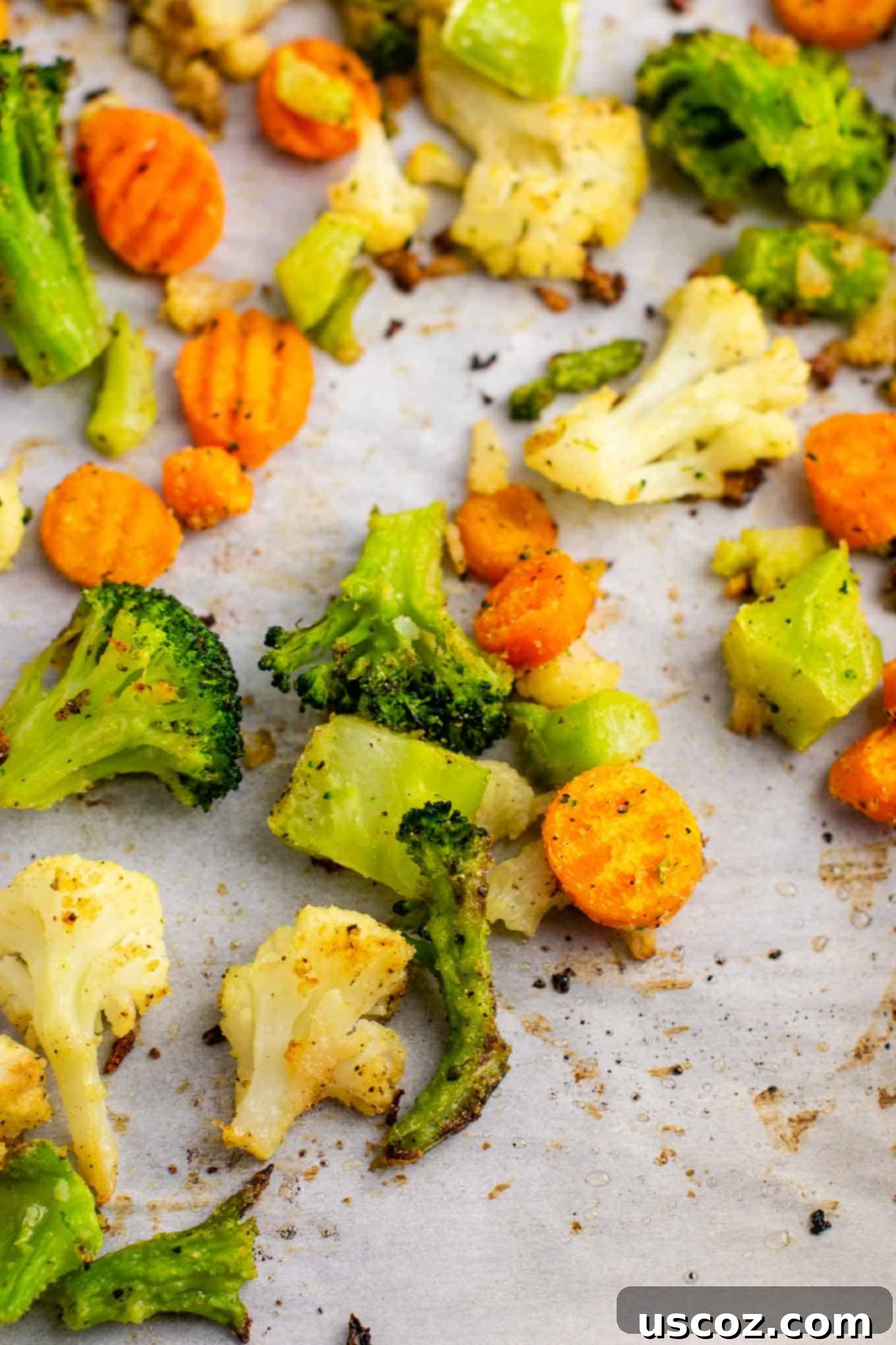 Easy Roasted Frozen Vegetables 3 broccoli, cauliflower, and carrots roasted on a parchment paper lined baking sheet