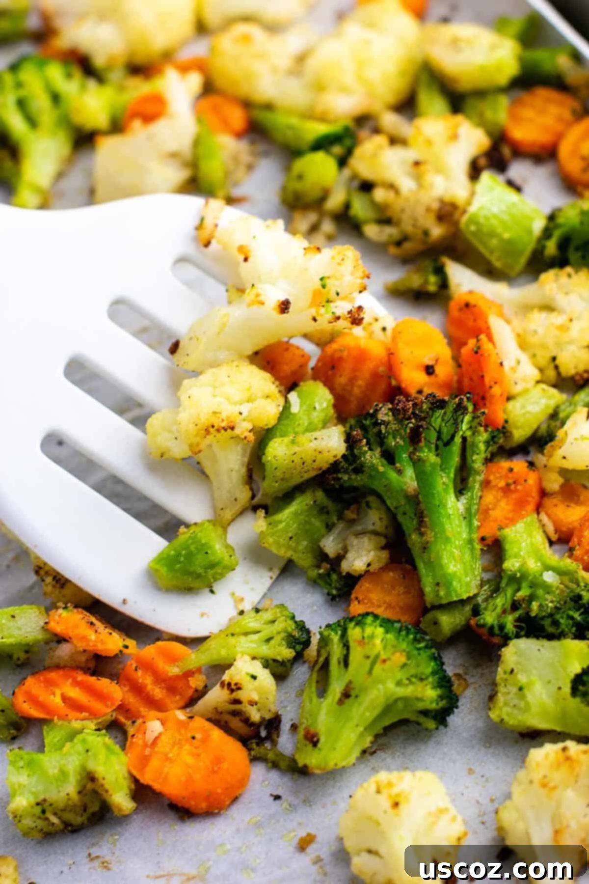 Easy Roasted Frozen Vegetables 5 a white spatula taking a scoop of roasted vegetables