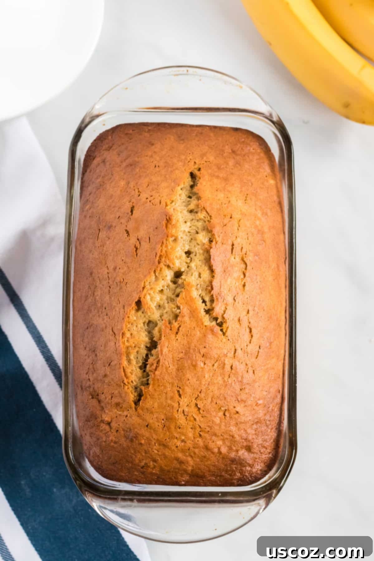 Effortless Cake Mix Banana Bread 8 A golden-brown cake mix banana bread loaf cooling in a clear glass loaf pan.