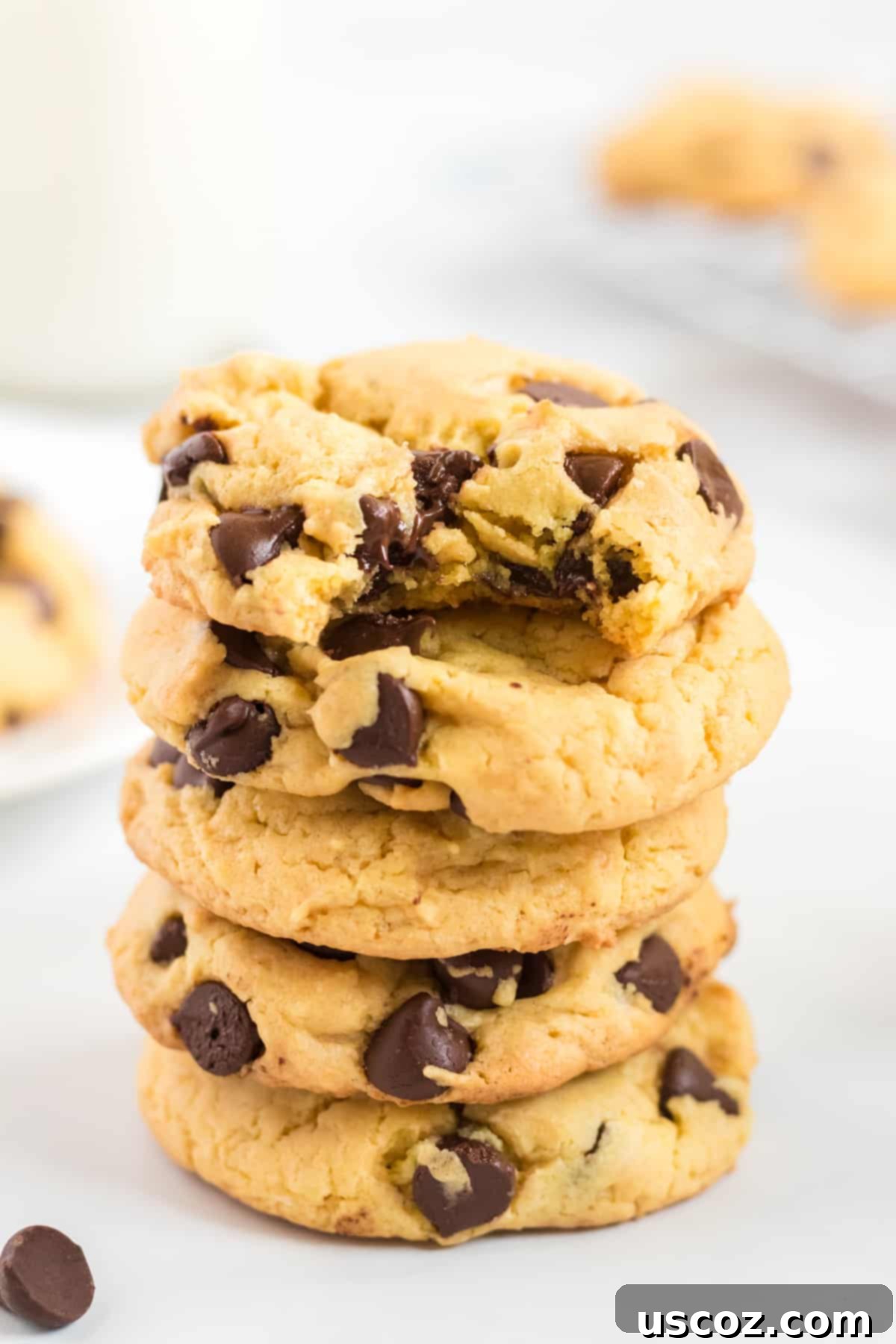 Shortcut Chocolate Chip Cookies 20 A stack of golden yellow cake mix cookies with the top one having a bite taken out, revealing its soft interior and melted chocolate chips.