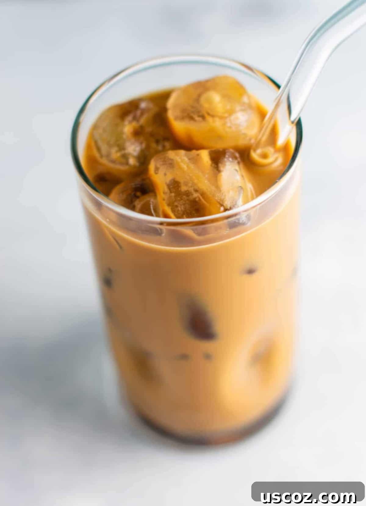 Effortless Instant Iced Coffee 7 A glass of homemade iced coffee with a straw, placed next to a jar of instant coffee and creamer, ready for customization.