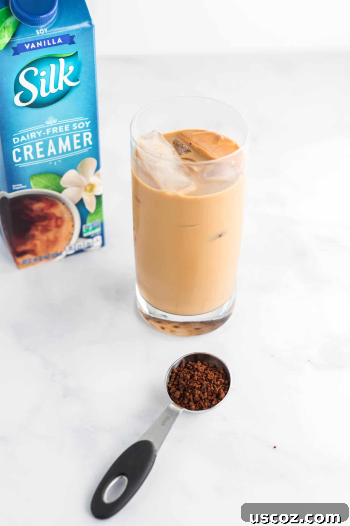Effortless Instant Iced Coffee 8 A trio of instant coffee ingredients: coffee grounds, a glass of prepared iced coffee, and a bottle of vanilla soy creamer.