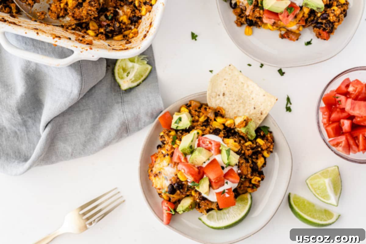 Wholesome Quinoa Enchilada Bake 3 A perfectly plated Mexican quinoa enchilada casserole, adorned with a dollop of sour cream, finely chopped tomatoes, creamy avocado, and a refreshing lime wedge, ready to be enjoyed.