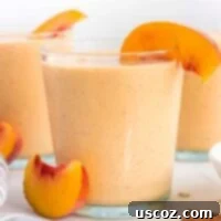 Sip into Summer: 11 Refreshing Smoothie Recipes 11 A delightful peach smoothie served in a glass, garnished with a fresh peach slice on the rim.