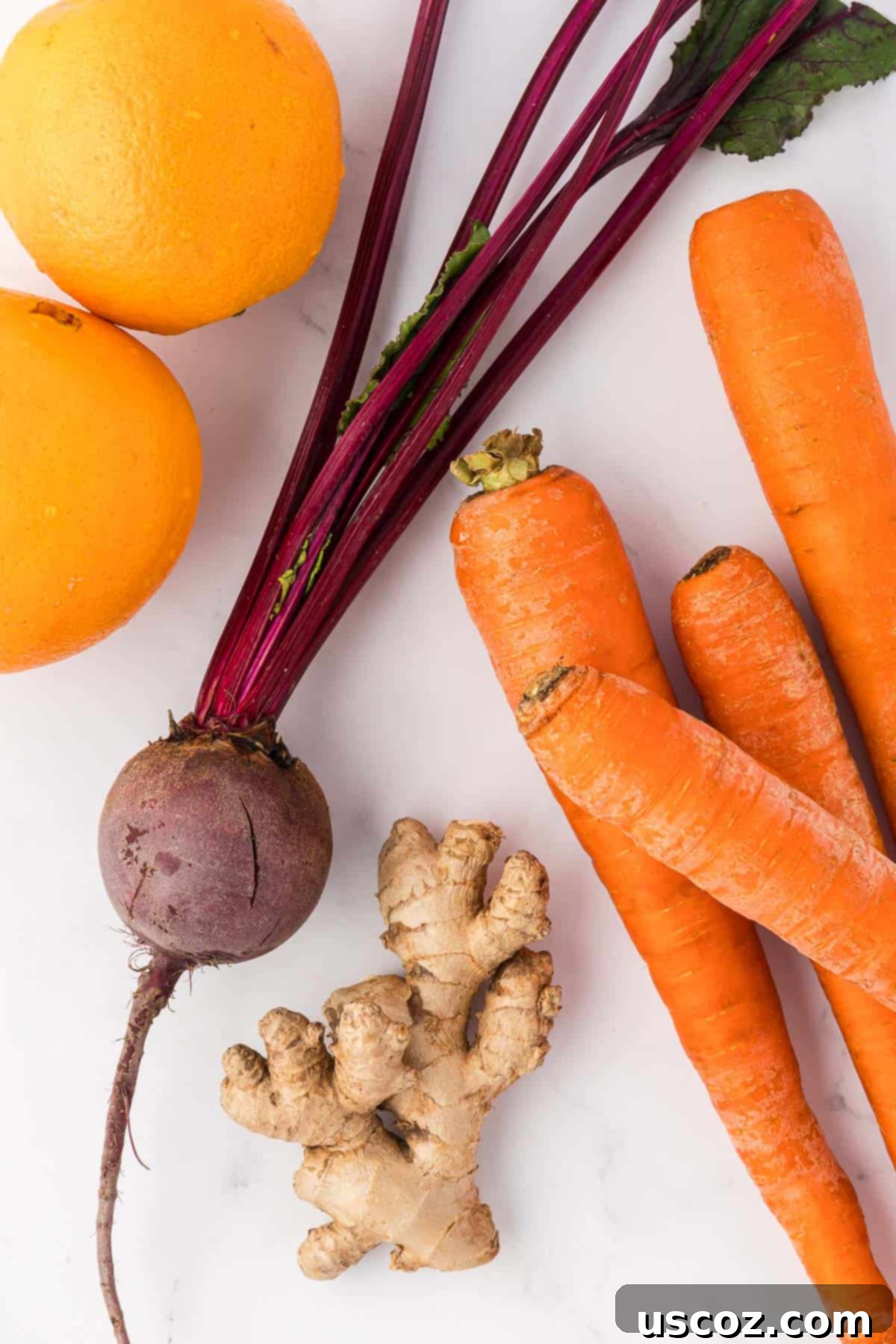 Ruby Root Refresher 4 Raw ingredients: fresh carrots, peeled oranges, a whole beet, and ginger root