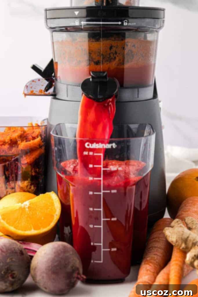 Ruby Root Refresher 5 Vibrant carrot beet juice pouring out of a juicer into a collection container