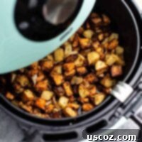 Crispy Air Fryer Breakfast Potatoes 11 Air fryer breakfast hash in an air fryer basket, featuring crispy sweet and russet potatoes