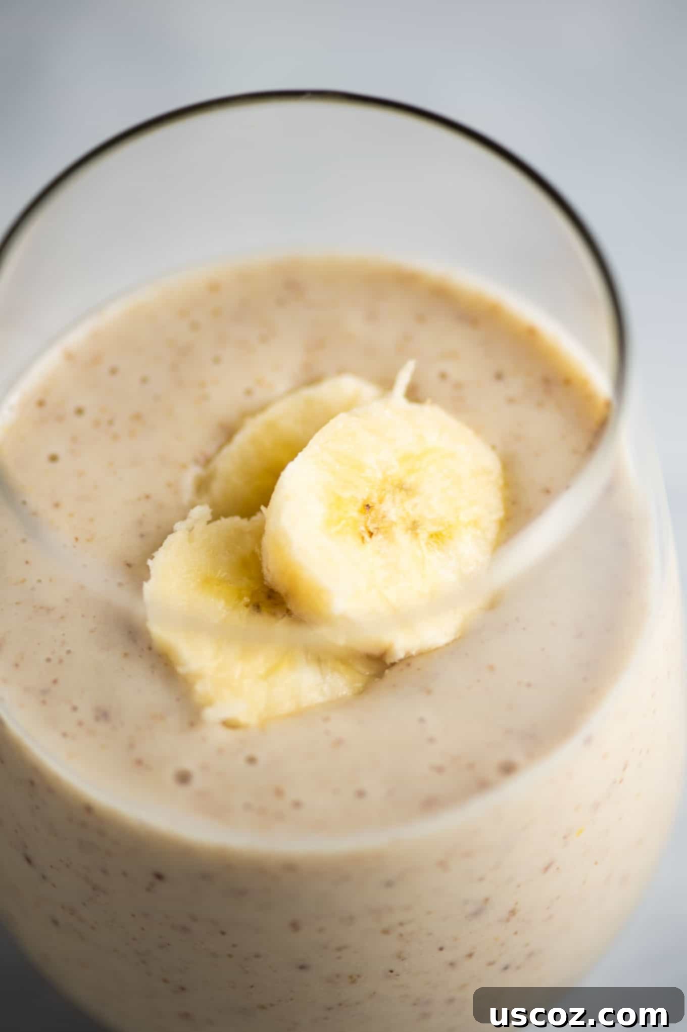Creamy Banana Delight 4 Refreshing banana smoothie in a glass, garnished with a banana slice, highlighting its smooth texture.