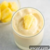 Tropical Pineapple Chill 11 frosty pineapple smoothie in a glass with frozen pineapple on top