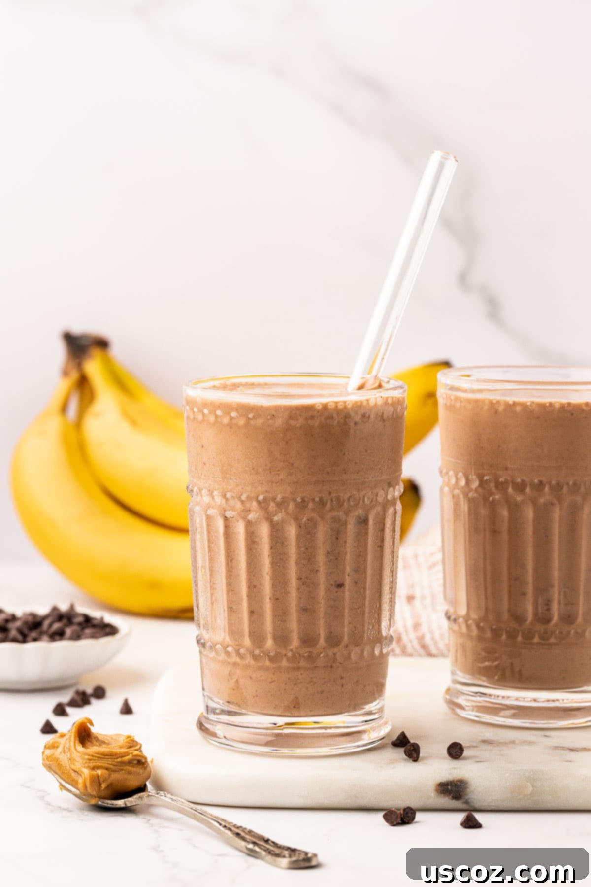 Indulgent Chocolate Peanut Butter Banana Smoothie 3 chocolate peanut butter banana smoothie in a tall glass with a straw, ready to drink
