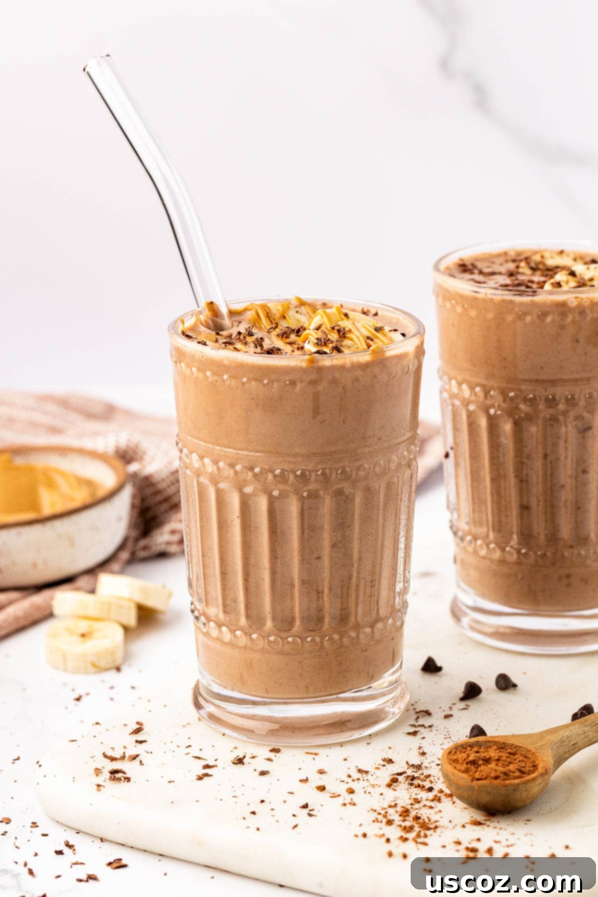 Indulgent Chocolate Peanut Butter Banana Smoothie 10 chocolate peanut butter banana smoothie in a glass with a straw on a wooden table
