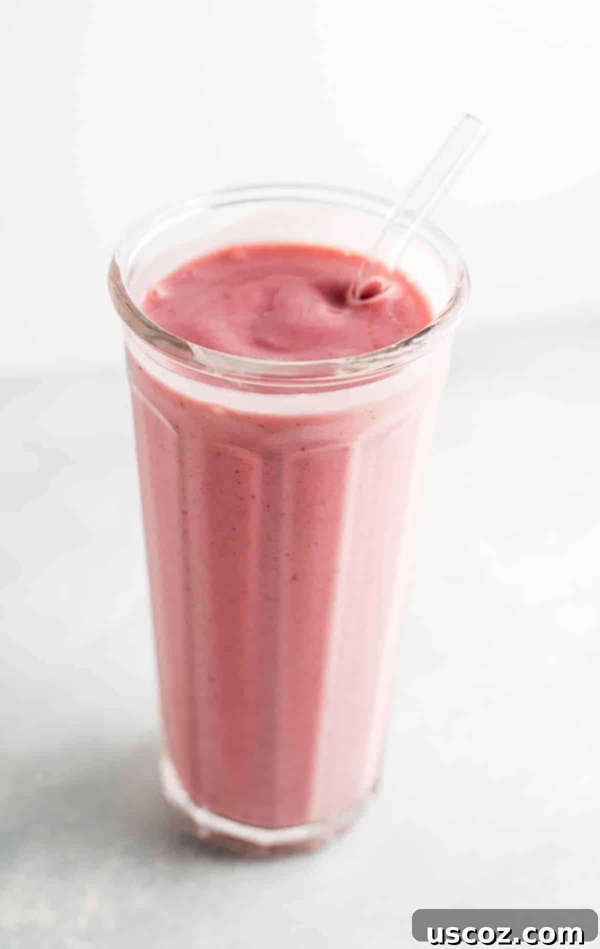 strawberry banana yogurt smoothie in a glass with a straw, garnished with a fresh strawberry