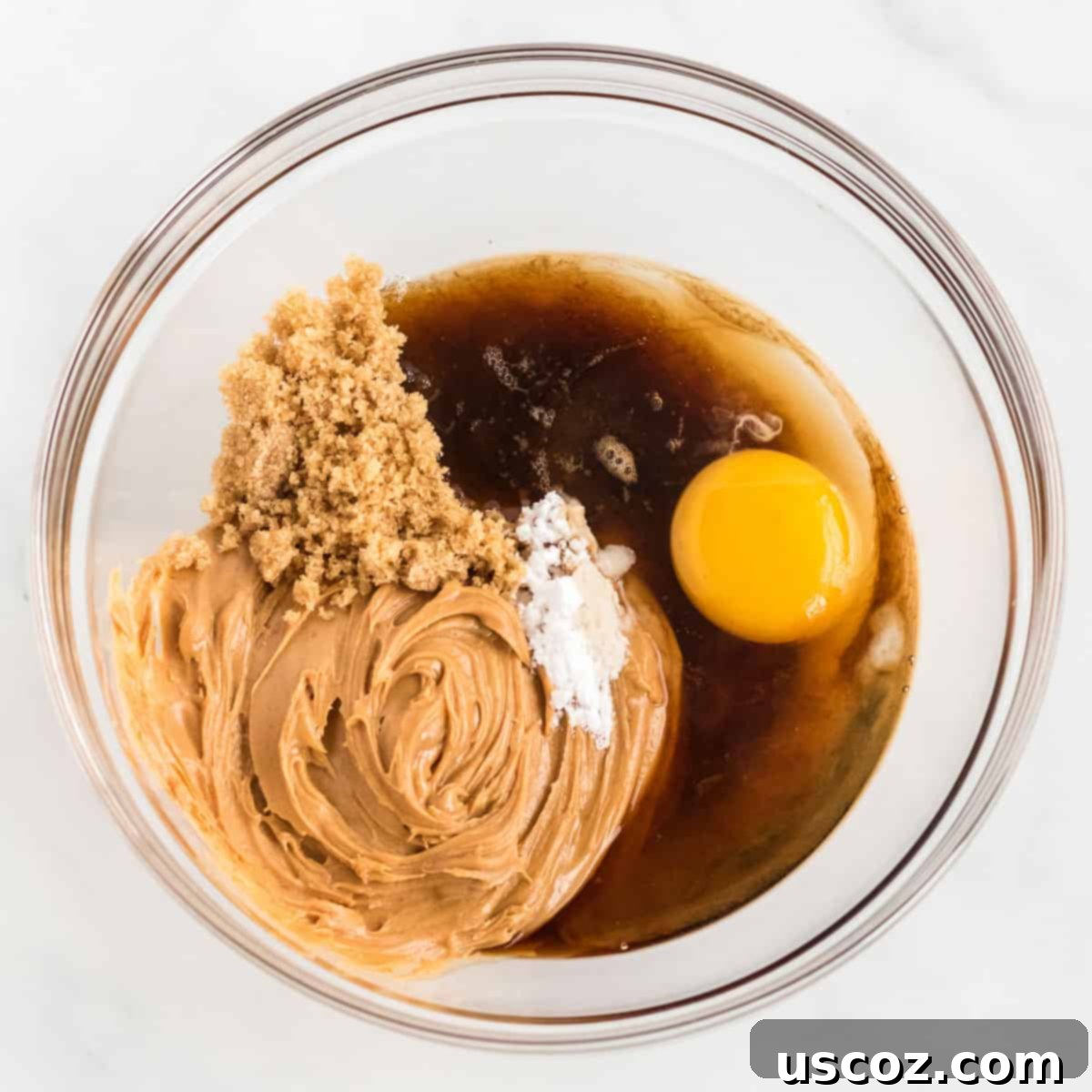 Irresistible Gluten-Free Peanut Butter Cookies 4 All six ingredients for gluten-free peanut butter cookies are added to a large mixing bowl, showing the initial stage of preparing the dough.