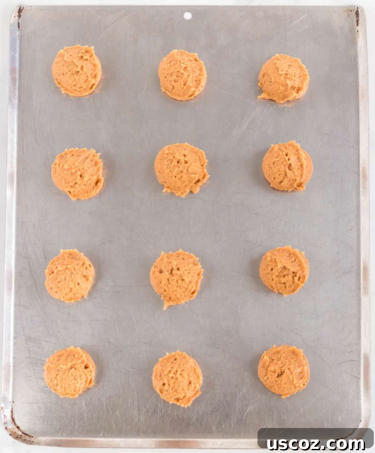 Irresistible Gluten-Free Peanut Butter Cookies 6 Sixteen evenly rolled balls of gluten free peanut butter cookie dough arranged on a parchment-lined baking sheet, ready for the next step.