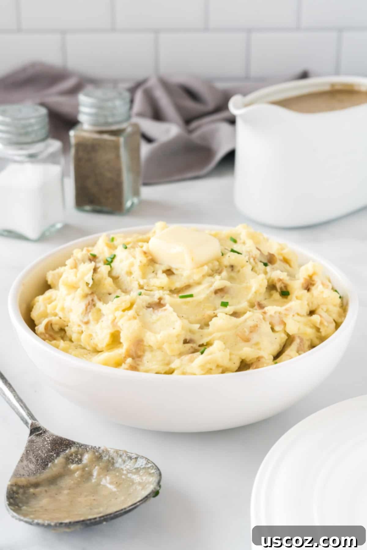 Tangy Mashed Potatoes 11 mashed potatoes in a bowl topped with butter and chives