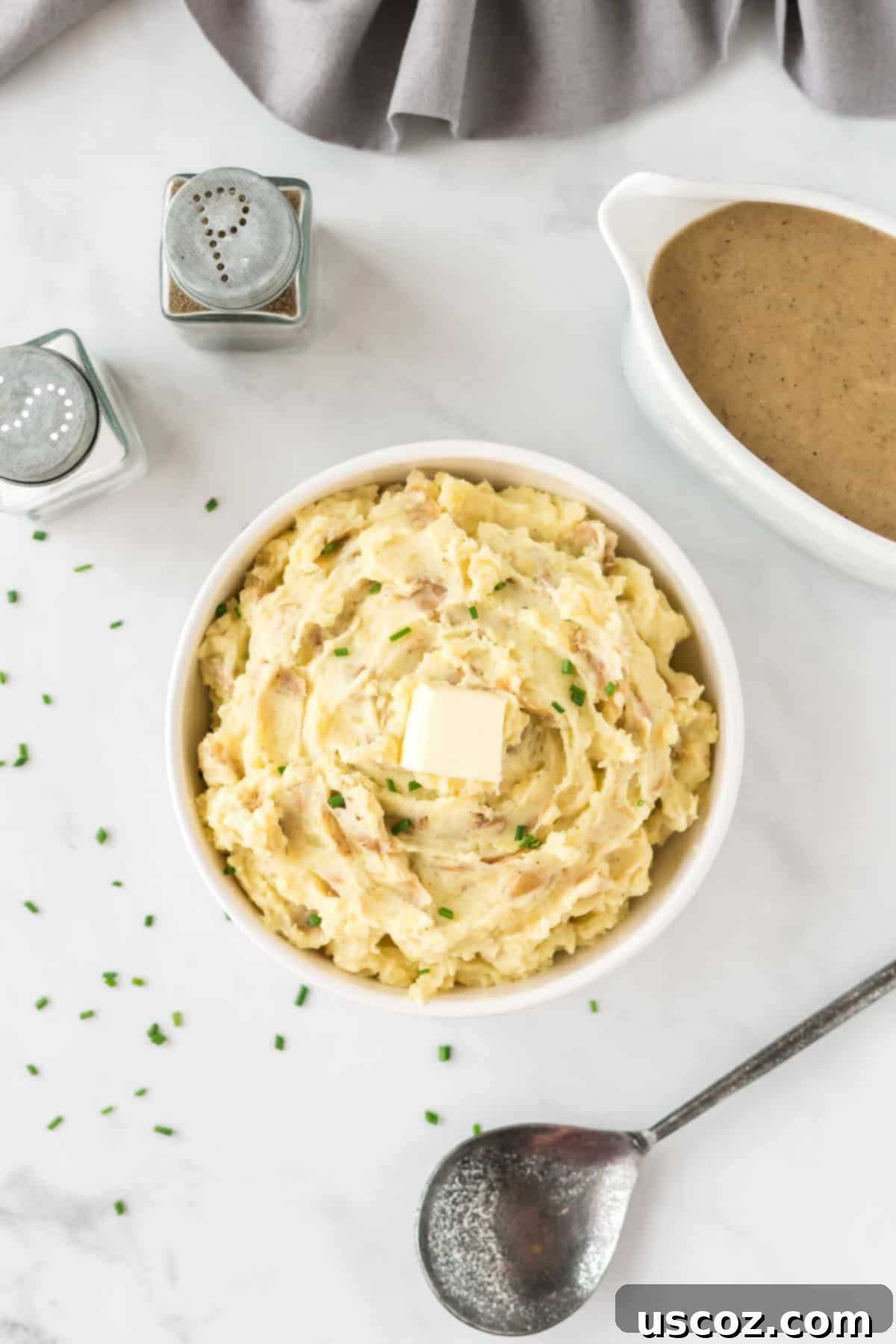 Tangy Mashed Potatoes 13 mashed potatoes in a bowl topped with butter and chives