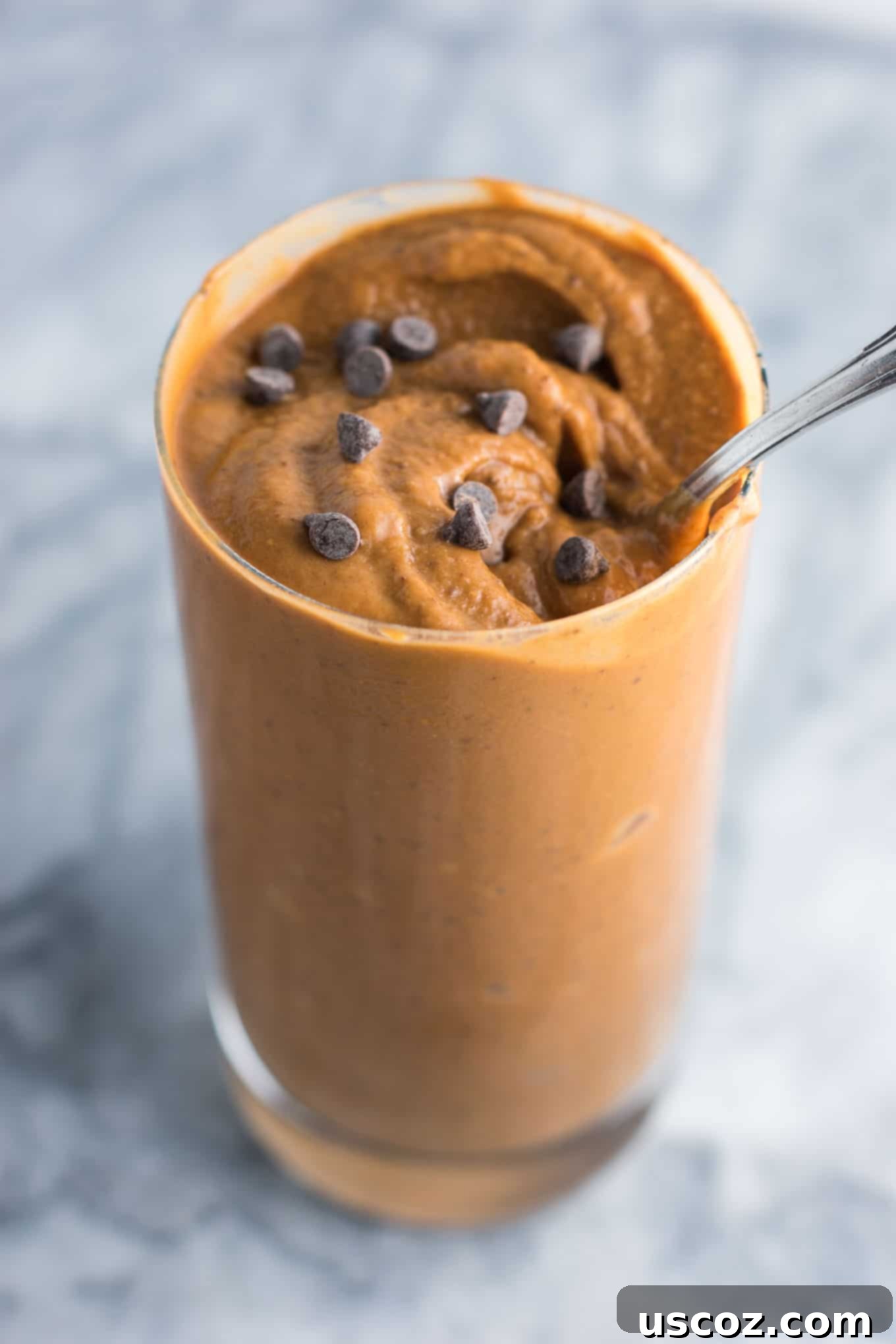 Indulgent double chocolate milkshake, sprinkled with mini chocolate chips in a glass with a spoon.