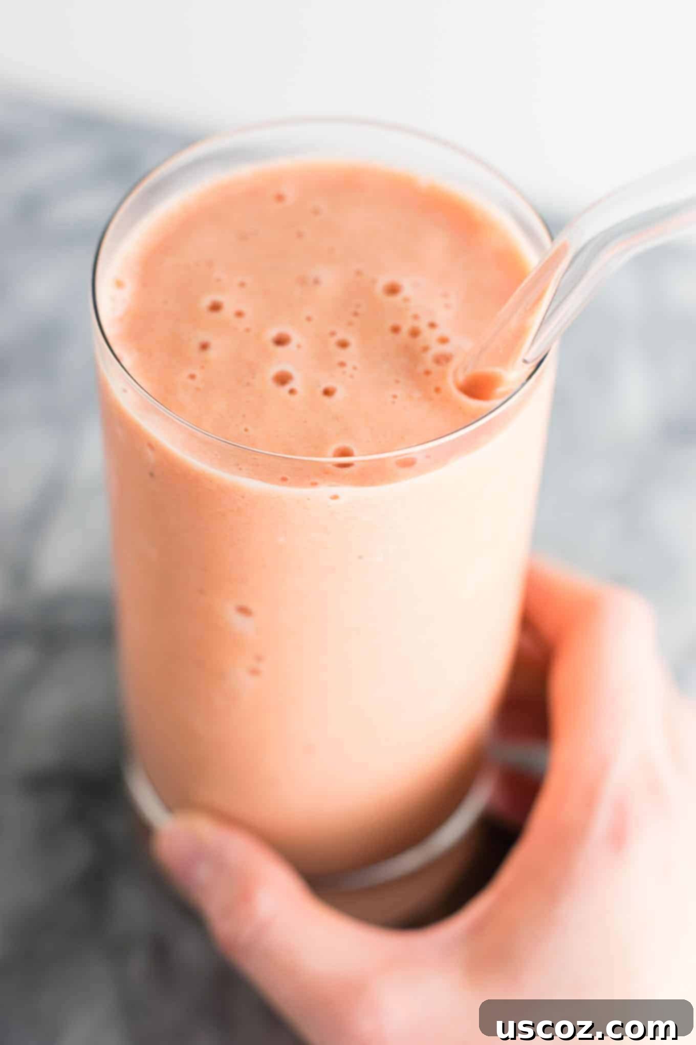 Hearty carrot cake smoothie recipe in a glass with a glass straw, combining healthy ingredients for a sweet treat.
