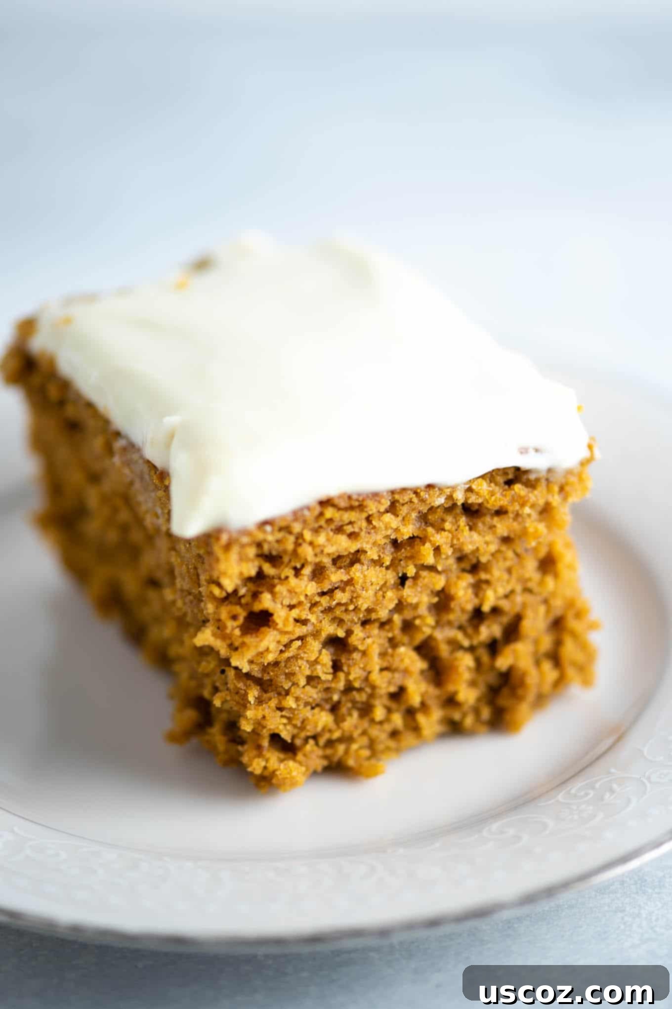 Decadent Pumpkin Cake with Cream Cheese Frosting 7 pumpkin cake slice with cream cheese frosting, garnished with a sprinkle of cinnamon