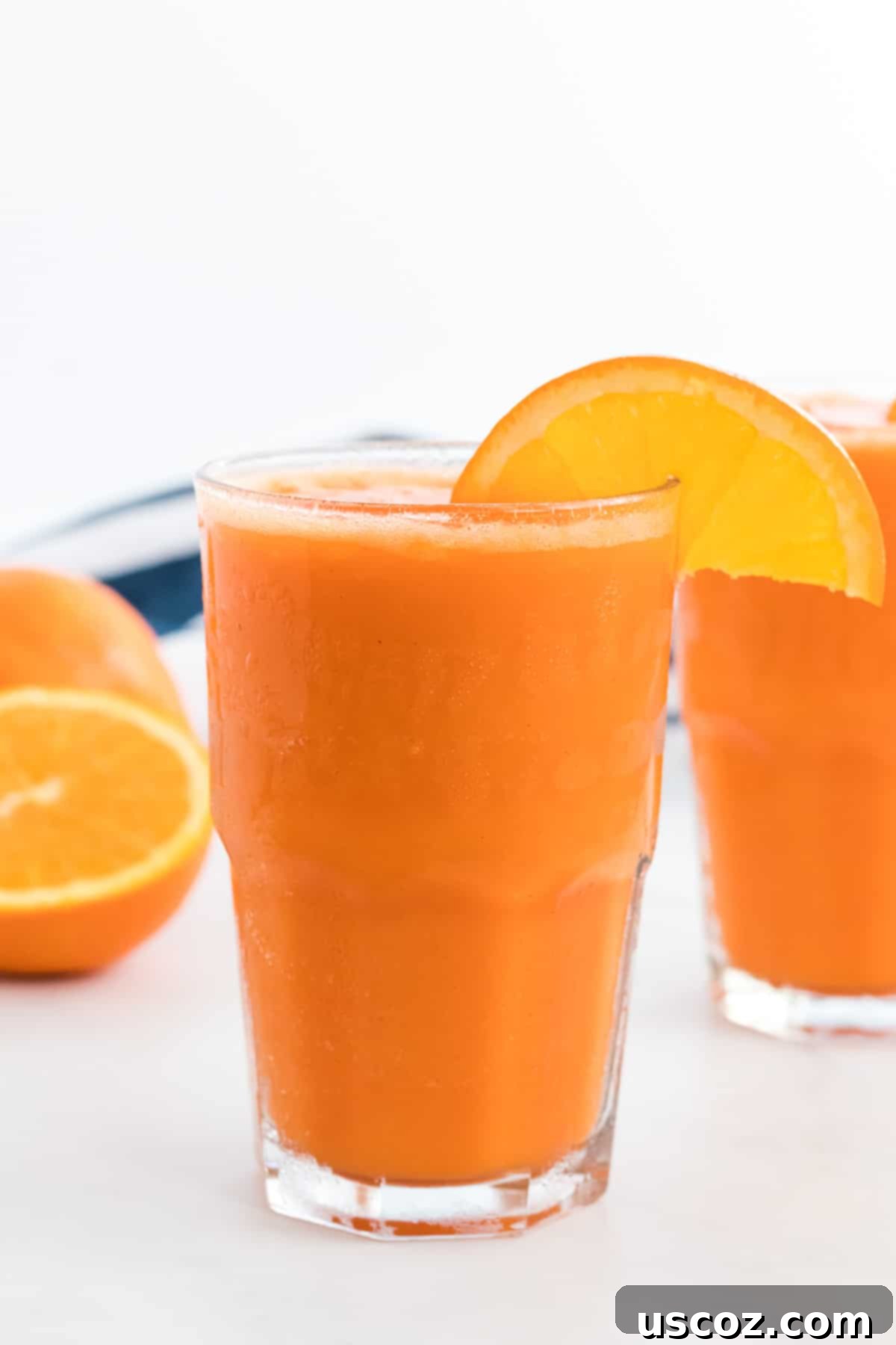 Golden Carrot Orange Smoothie 2 Vibrant carrot orange smoothie in a tall glass, garnished with a fresh orange slice on the rim, showcasing its refreshing appeal.