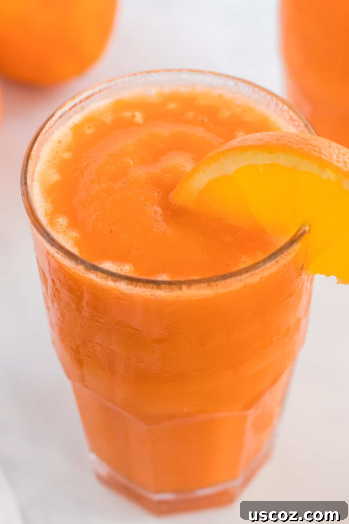 Golden Carrot Orange Smoothie 3 Close-up of a refreshing carrot orange smoothie in a glass, with a decorative orange slice on the rim, emphasizing its fresh and inviting appearance.