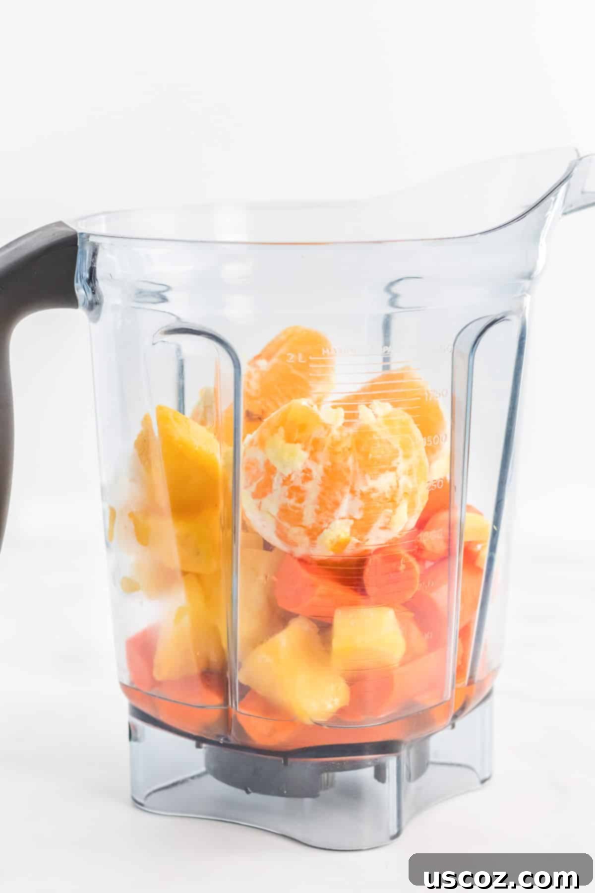Golden Carrot Orange Smoothie 6 Inside a high-speed blender, a vibrant orange mixture of carrot, orange, and pineapple ingredients is blending smoothly, demonstrating the power of the appliance.