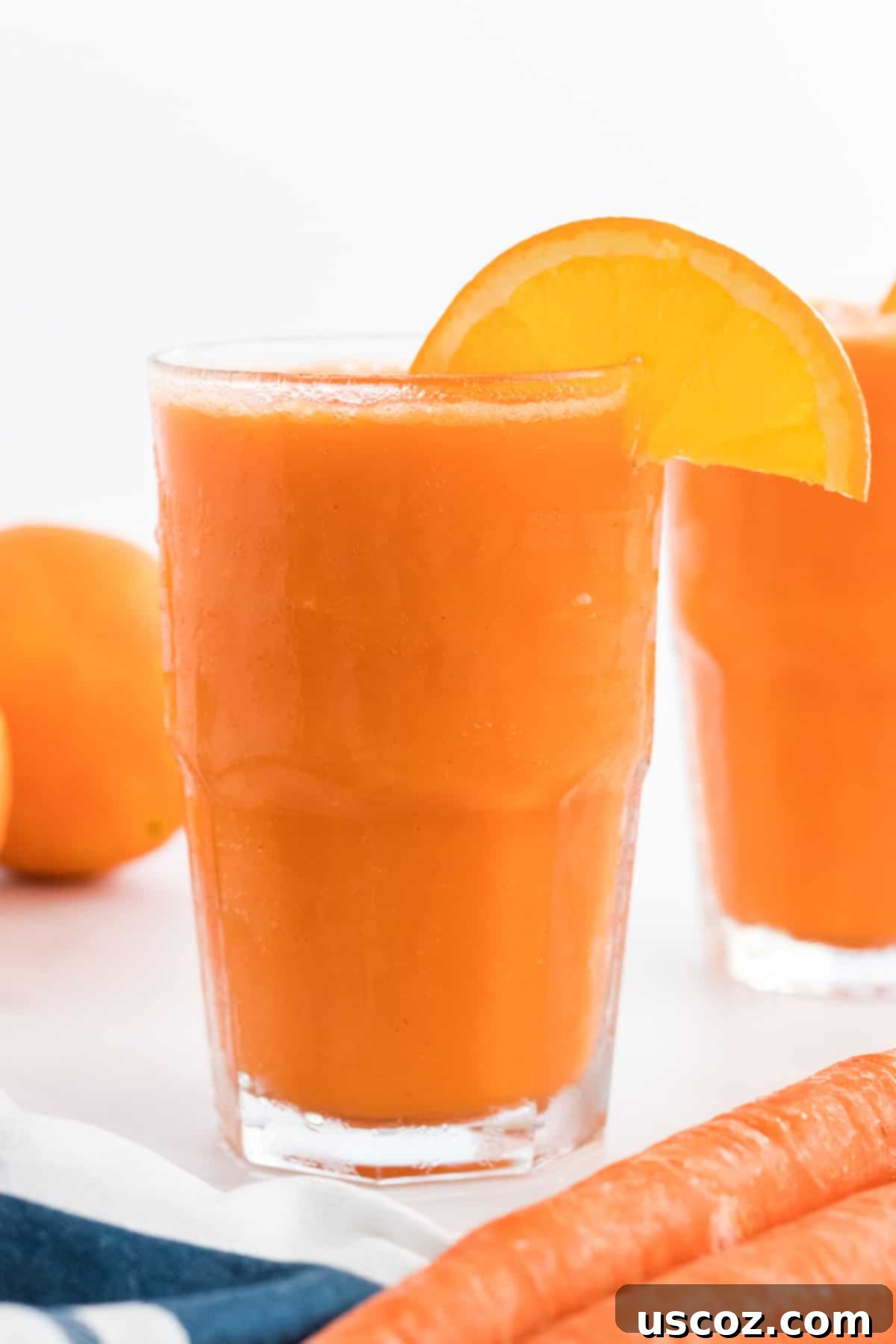Golden Carrot Orange Smoothie 9 A close-up of a single glass of carrot orange smoothie with an orange slice on the rim, emphasizing its refreshing and healthful qualities.