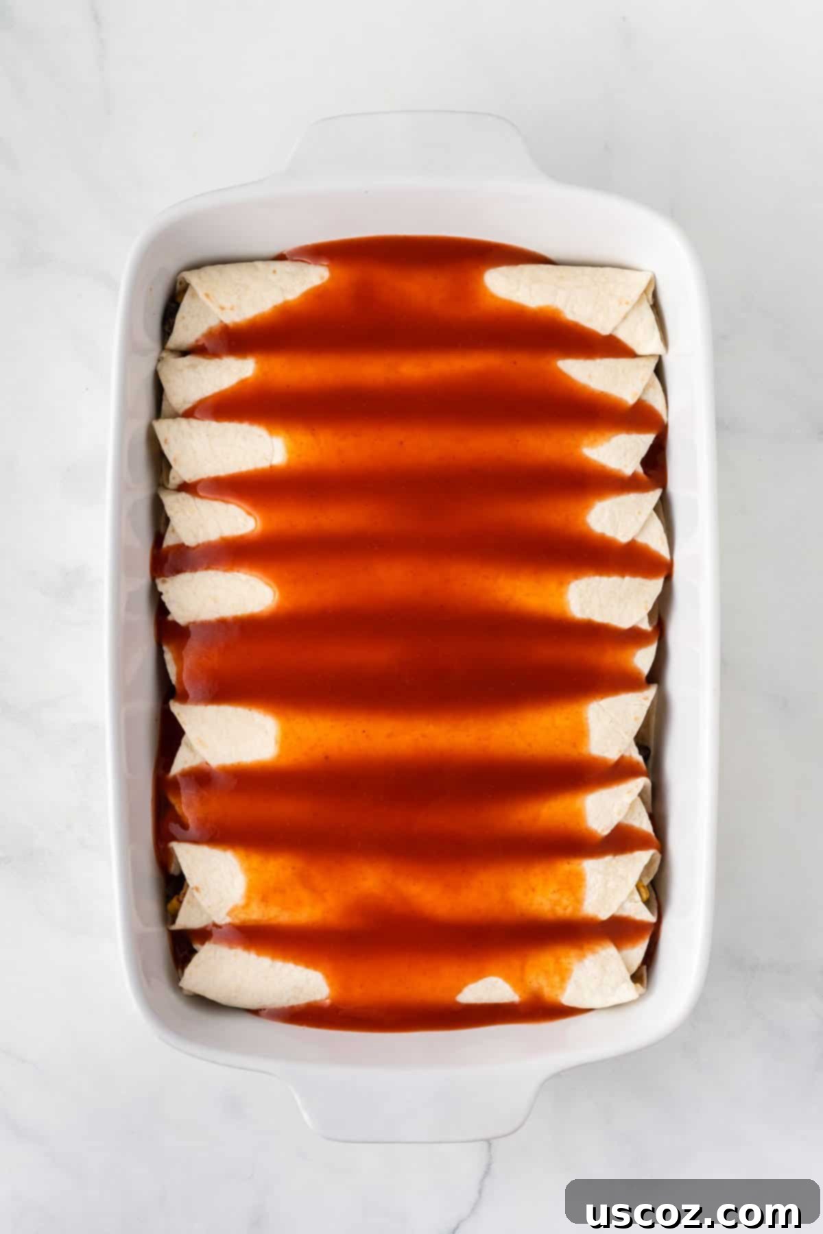 Irresistible Vegetarian Enchiladas 13 pouring enchilada sauce over the enchiladas
