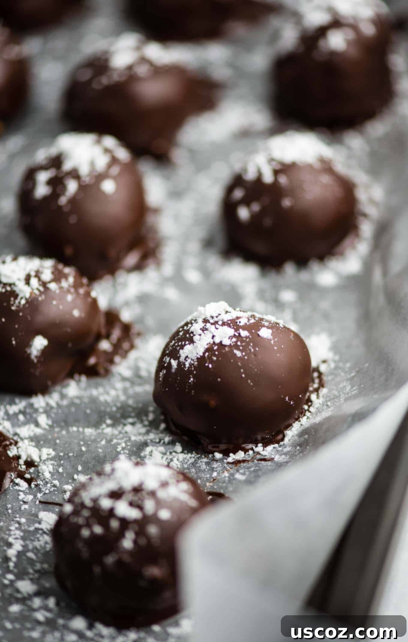 No-Bake Pumpkin Cheesecake Delights 6 truffles lined up on the baking sheet sprinkled with powdered sugar