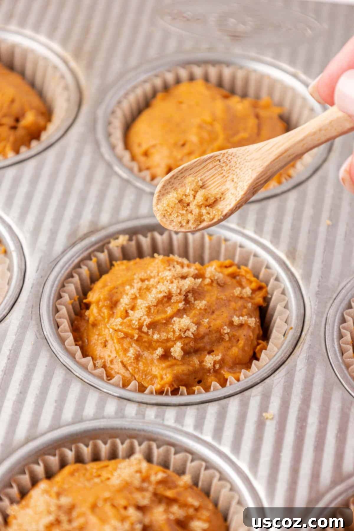 Effortless Cake Mix Pumpkin Muffins 8 sprinkling brown sugar on top of pumpkin muffin batter