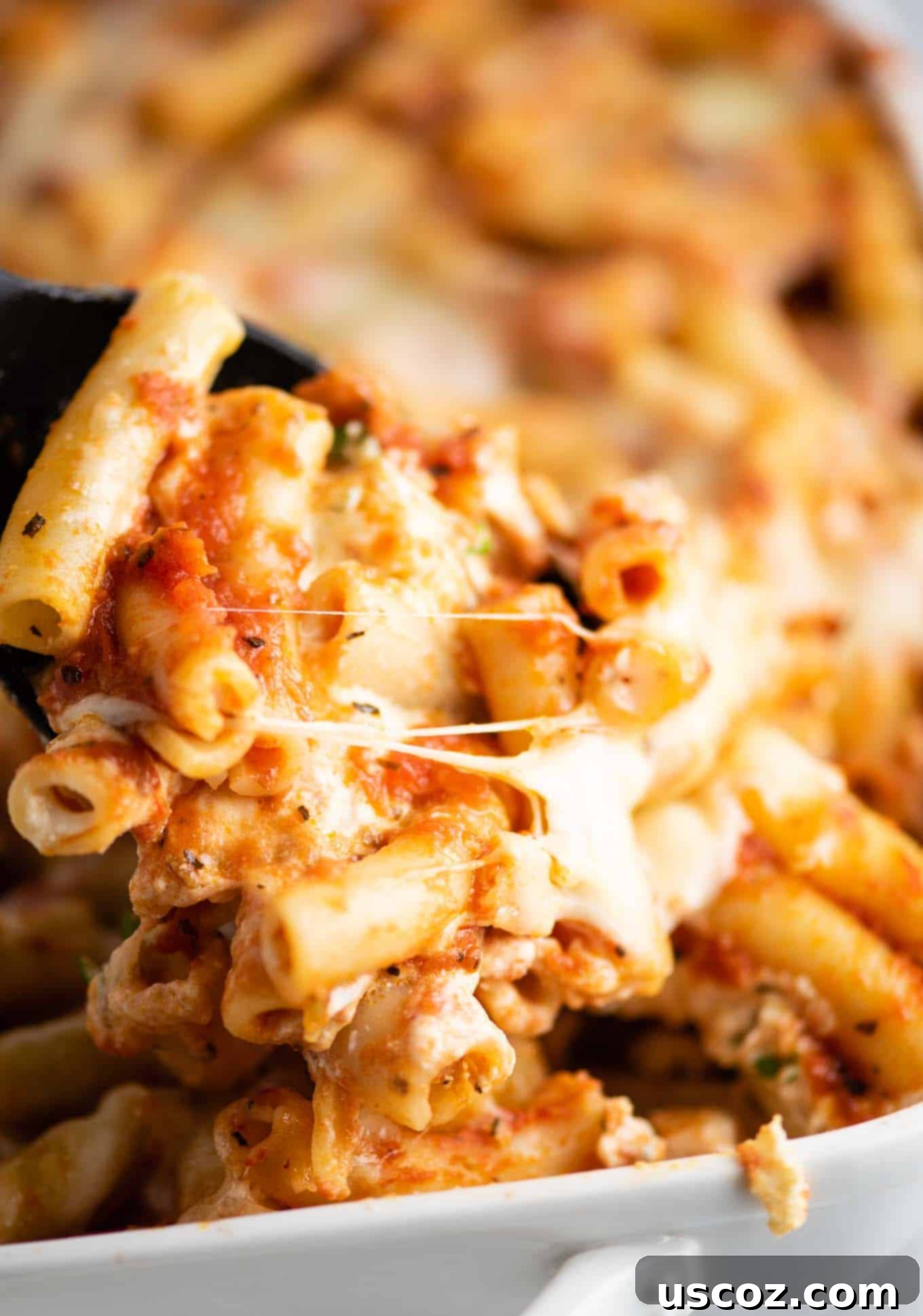 Ultimate Triple Cheese Baked Ziti 6 scoop of baked ziti coming out of the dish, highlighting a satisfying melted cheese pull