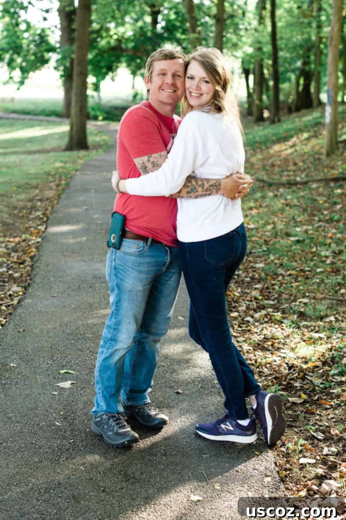 a couple hugging in a park with trees in the background