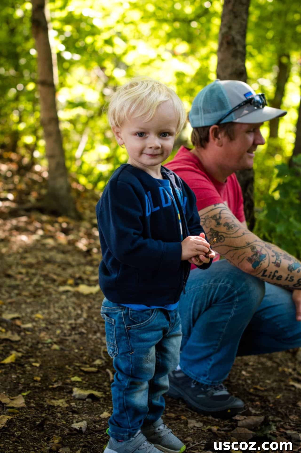toddler boy smiling with dad in the background
