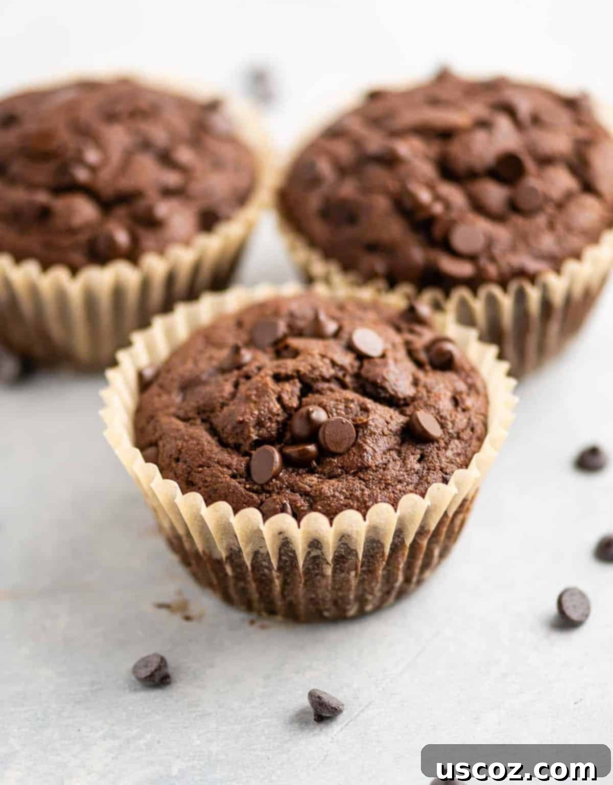 three chocolate muffins with the liners on