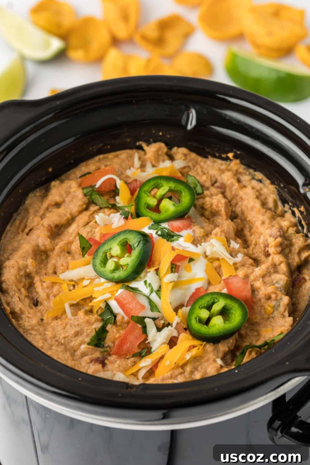 Slow Cooker Fiesta Bean Dip 12 bean dip in a crock pot topped with jalapenos, cheese, and tomatoes