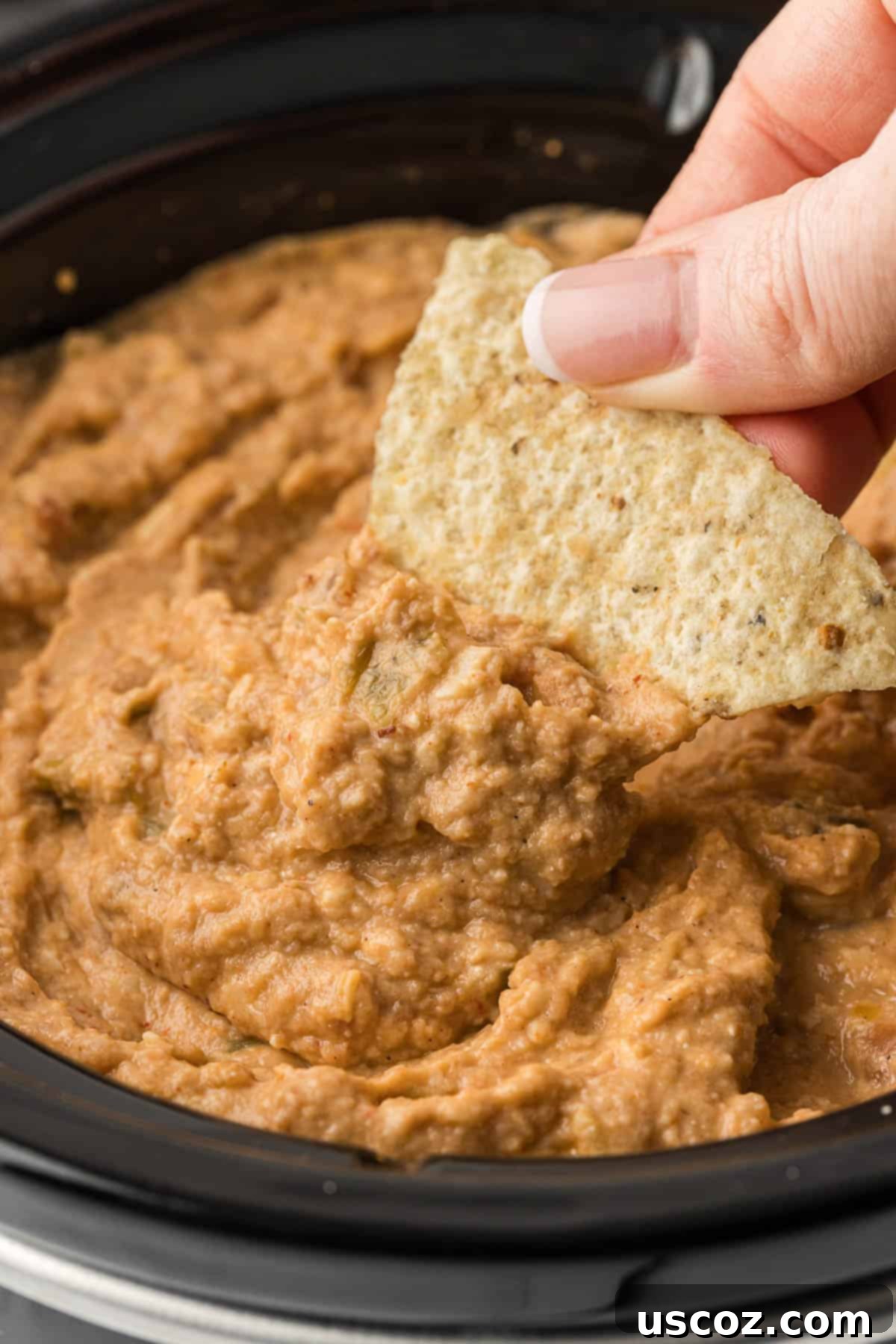 Slow Cooker Fiesta Bean Dip 7 dipping a tortilla chip into bean dip