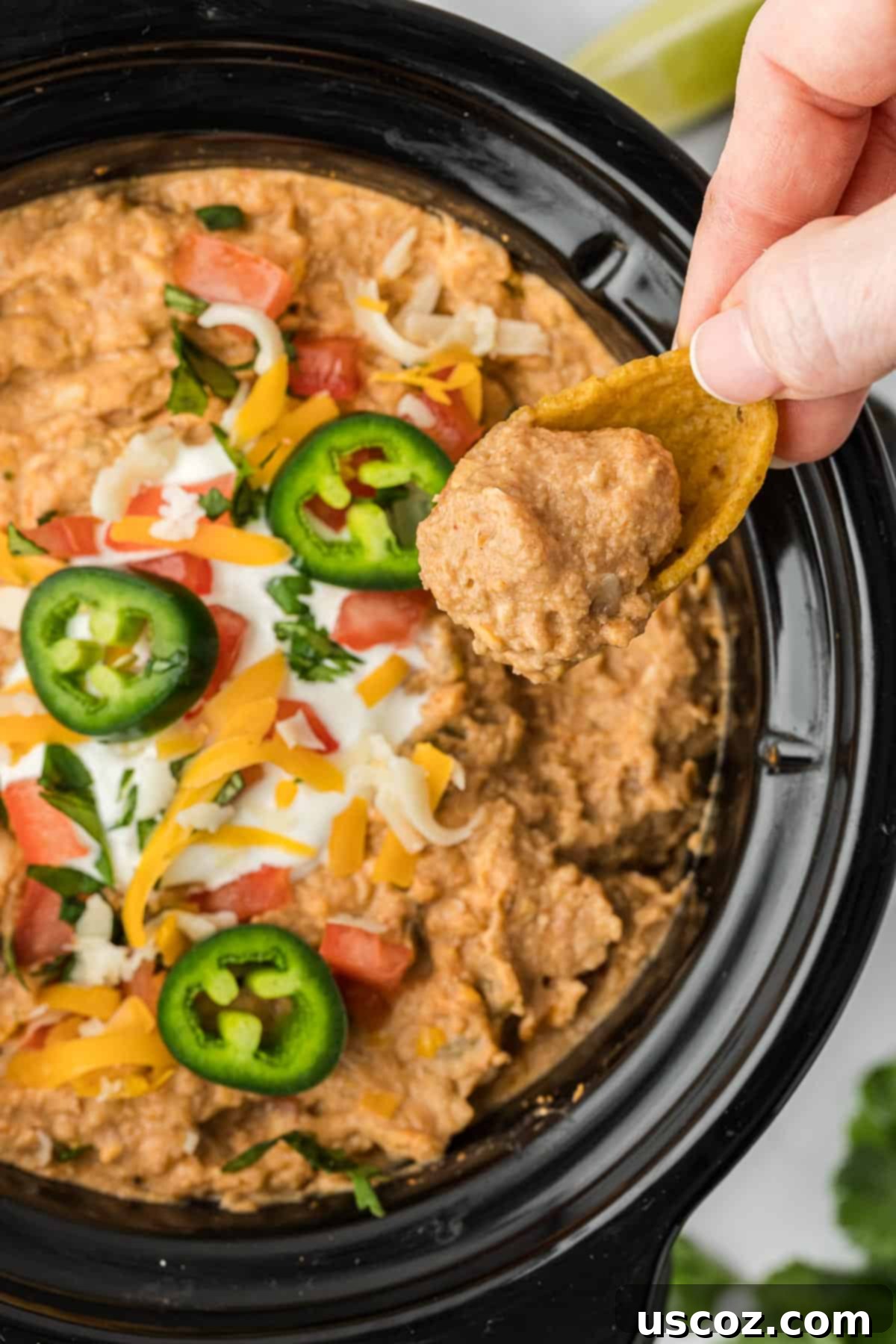 Slow Cooker Fiesta Bean Dip 10 dipping a tortilla chip into bean dip
