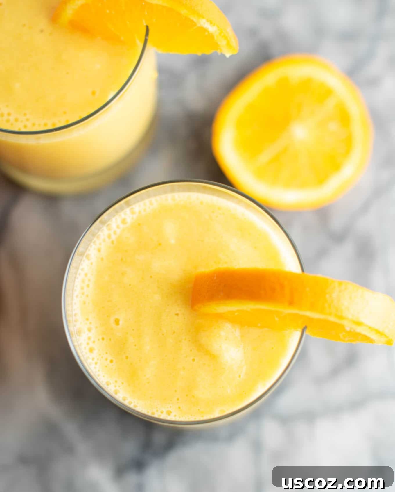 Sunshine Orange Smoothie 5 Close-up overhead shot of a single fresh orange smoothie in a clear glass, showing the creamy texture and vibrant orange color.
