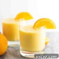 Sunshine Orange Smoothie 7 Fresh orange smoothie in a clear glass with an orange slice on the rim, showcasing its vibrant color and creamy texture.