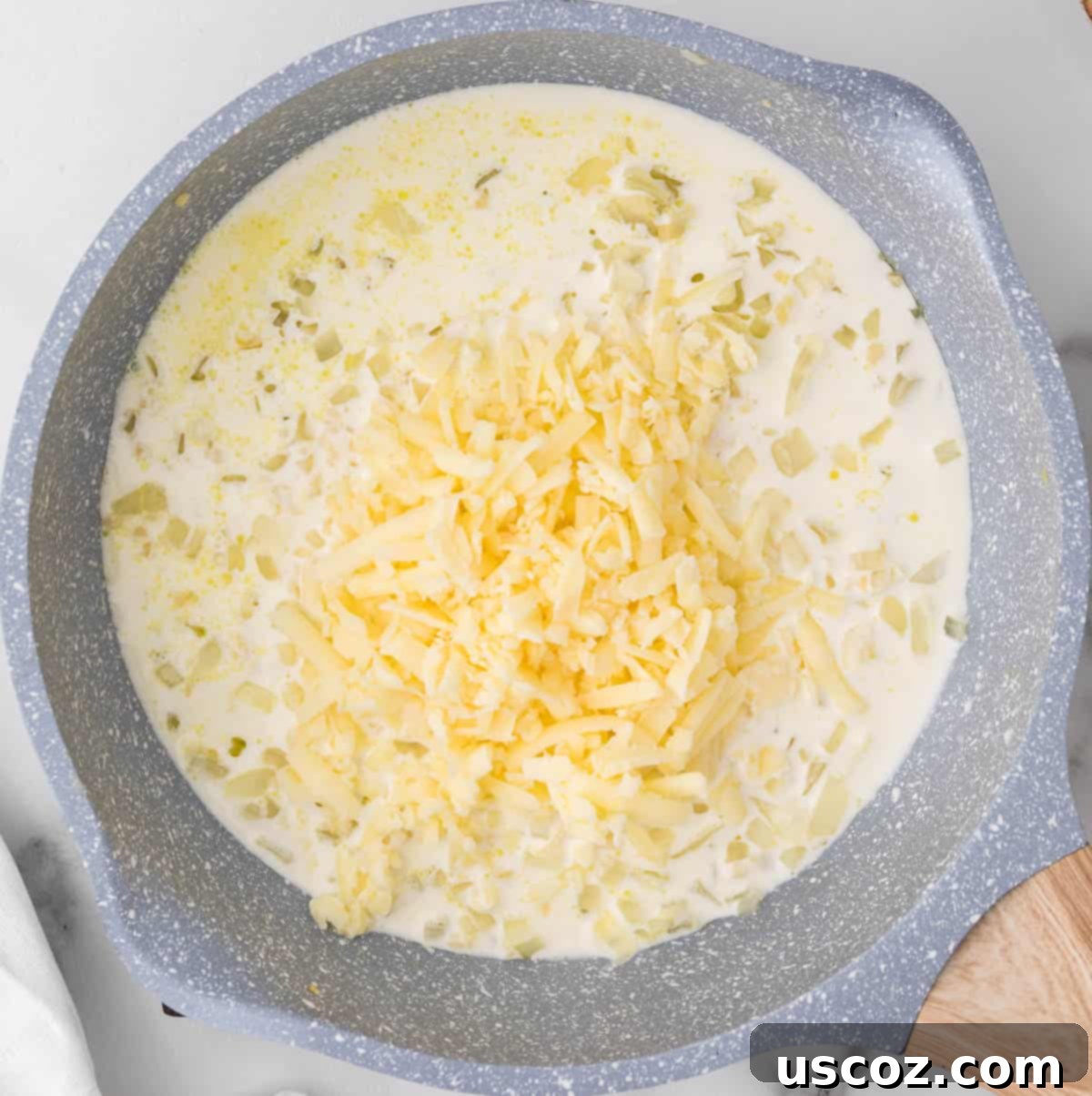 Golden Cheesy Brussels 8 Adding shredded sharp white cheddar cheese to the creamy sauce in a skillet.