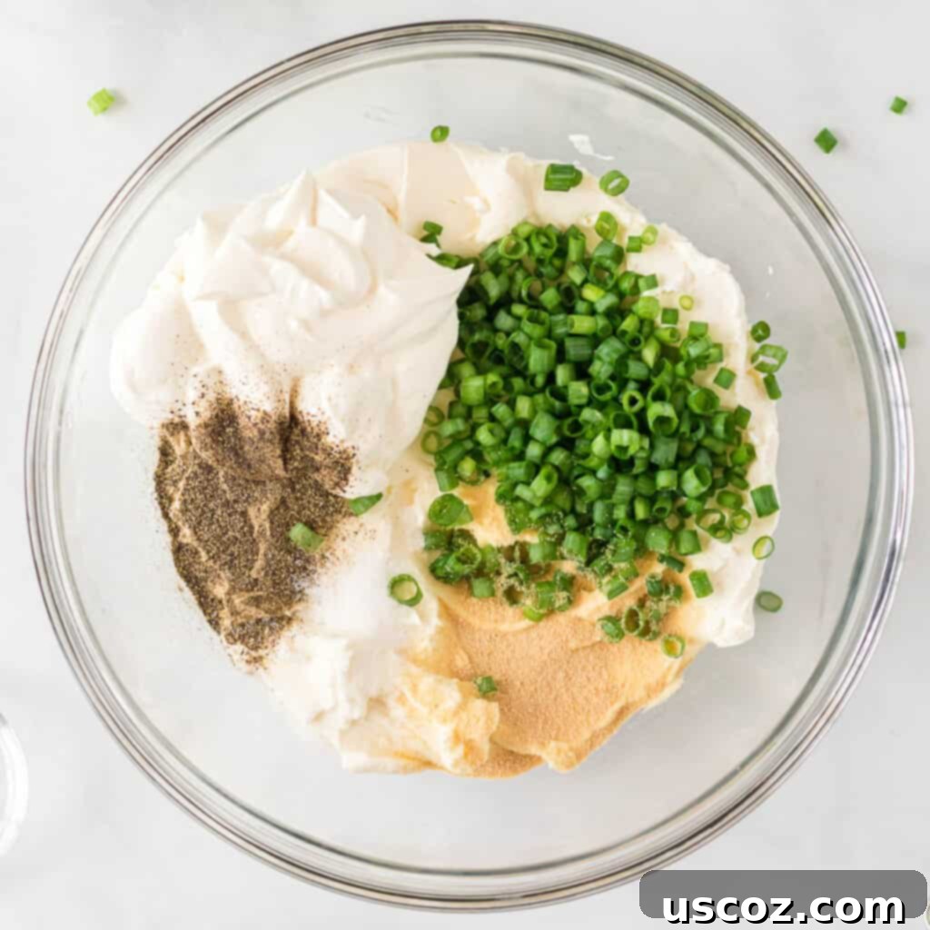 Party Perfect Cheese Ball 5 Bowl filled with softened cream cheese, sour cream, finely chopped green onions, and spices, ready for mixing.