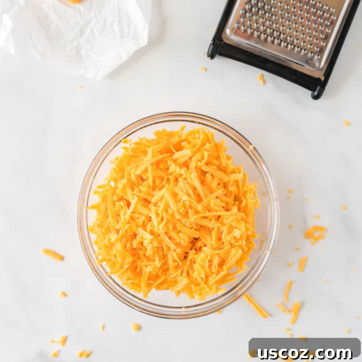 Party Perfect Cheese Ball 7 Bowl filled with freshly shredded sharp cheddar cheese, ready to be added to the cheese ball mixture.