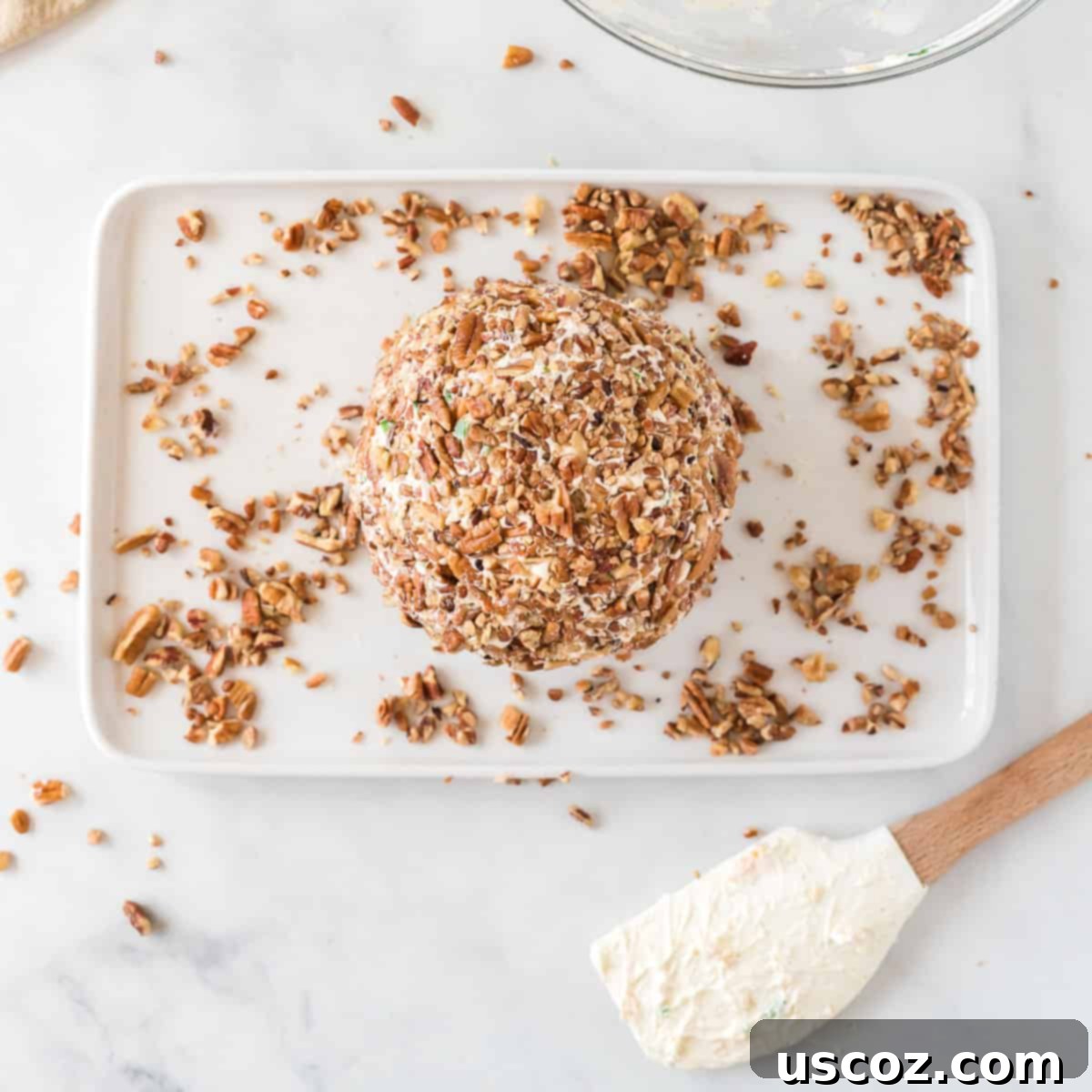 Party Perfect Cheese Ball 10 A finished cheese ball, completely coated in chopped pecans, sitting on a serving plate.
