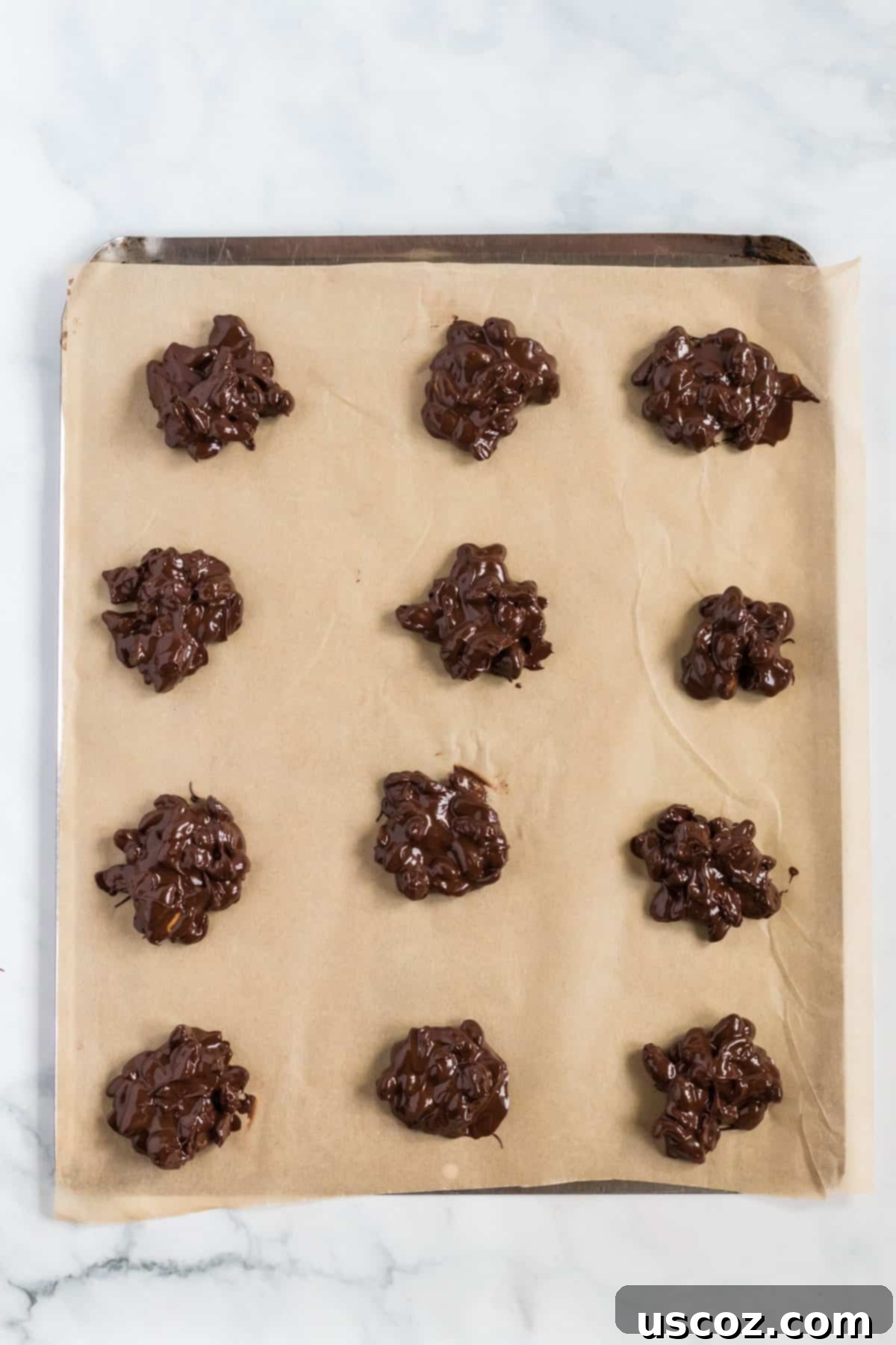 Crunchy Peanut Delights 7 Chocolate peanut clusters neatly arranged on a parchment paper-lined baking sheet, awaiting chilling.